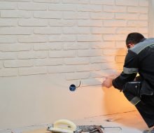 Master lays tiles on the wall. Builder installs tiles for renovation work, wall decor sticker in apartment
