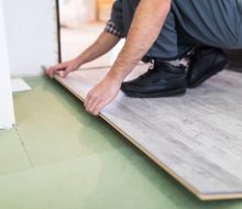 Young worker laying a floor with bright laminated flooring boards